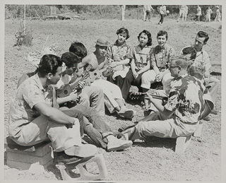 A group of singing young people sitting in a group outside, 1948