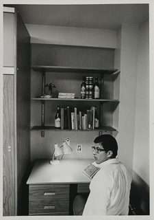 Student sitting at their desk in a residence hall, 1980