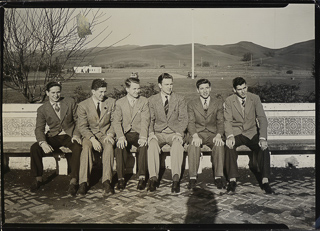 Members of the Society for Propagation of Faith sitting on the Senior&#39;s bench with train station in background, 1942