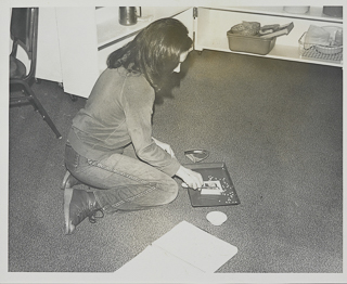 Student sitting on the floor manipulating beads, 2013