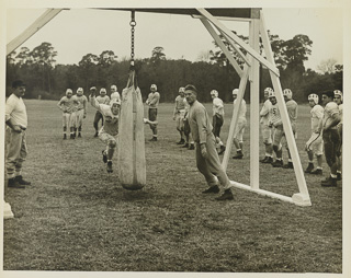 Wes Busch of the football team hitting a dummy during practice, undated