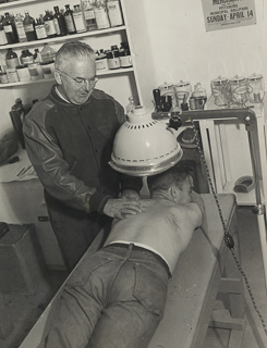 Athletic trainer William Fallon massaging student athlete, 1946