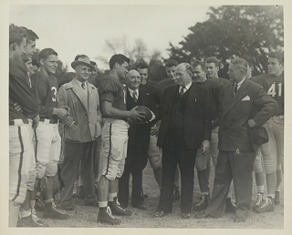 Herman John Wedemeyer presenting a football to an unidentified man during a ceremony after a football game, 1946