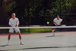 Two young men playing doubles tennis, April 1999