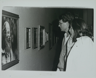 Art professor Suzanne Schumacher with unidentified man looking at a painting, 1985